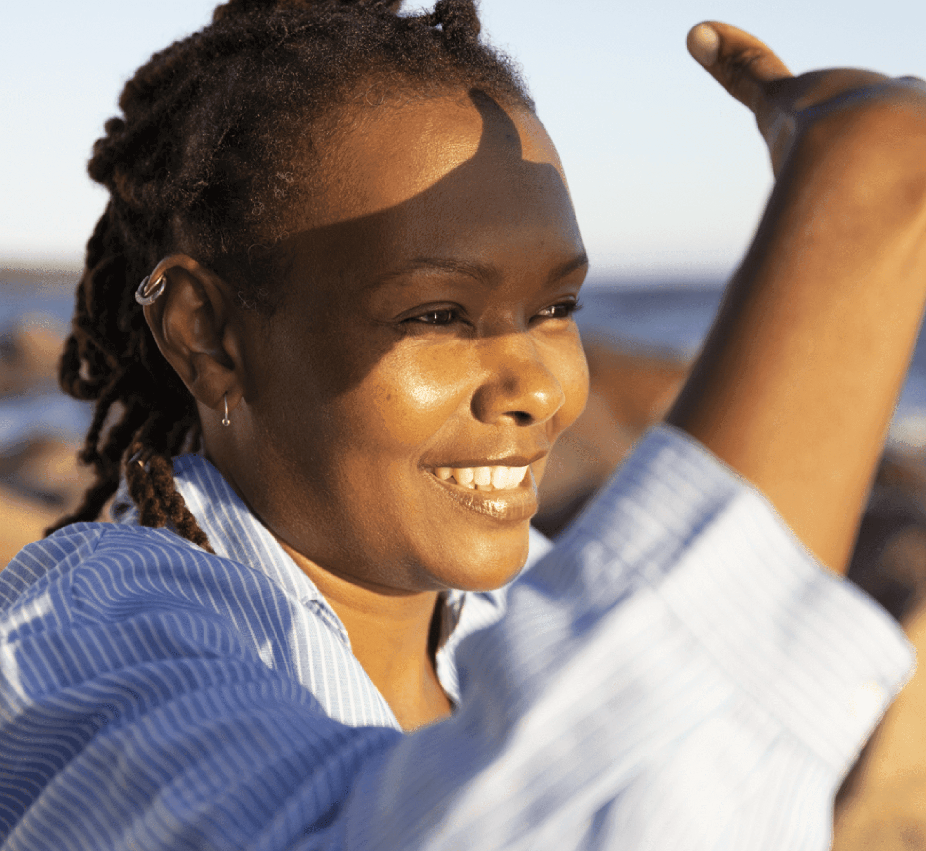A woman smiling by the sea, sunlight on her face