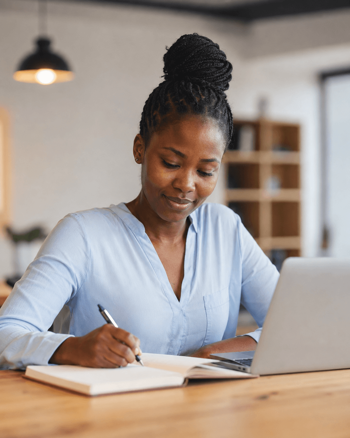 Writing notes beside a laptop at a desk